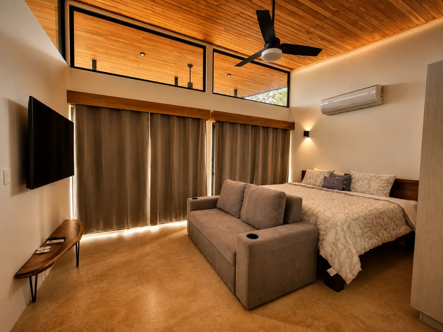 Studio interior with king bed, sofa, Smart TV, ceiling fan and air conditioning