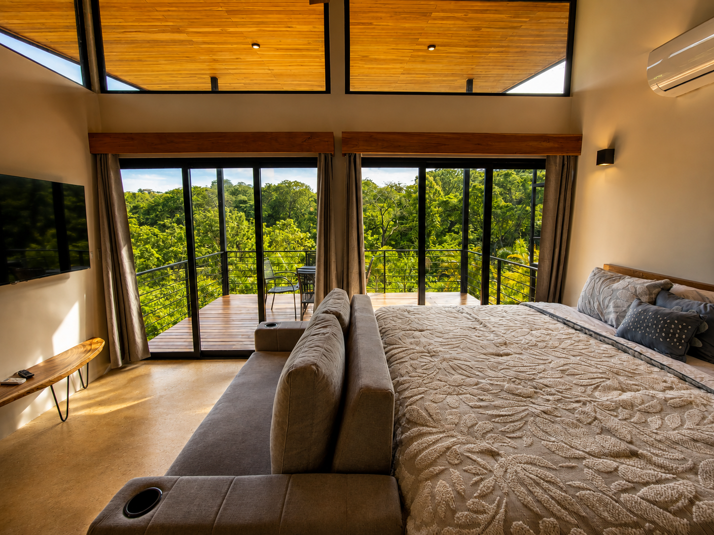 King bed and sleeper sofa facing full-height sliding doors onto the jungle-view deck