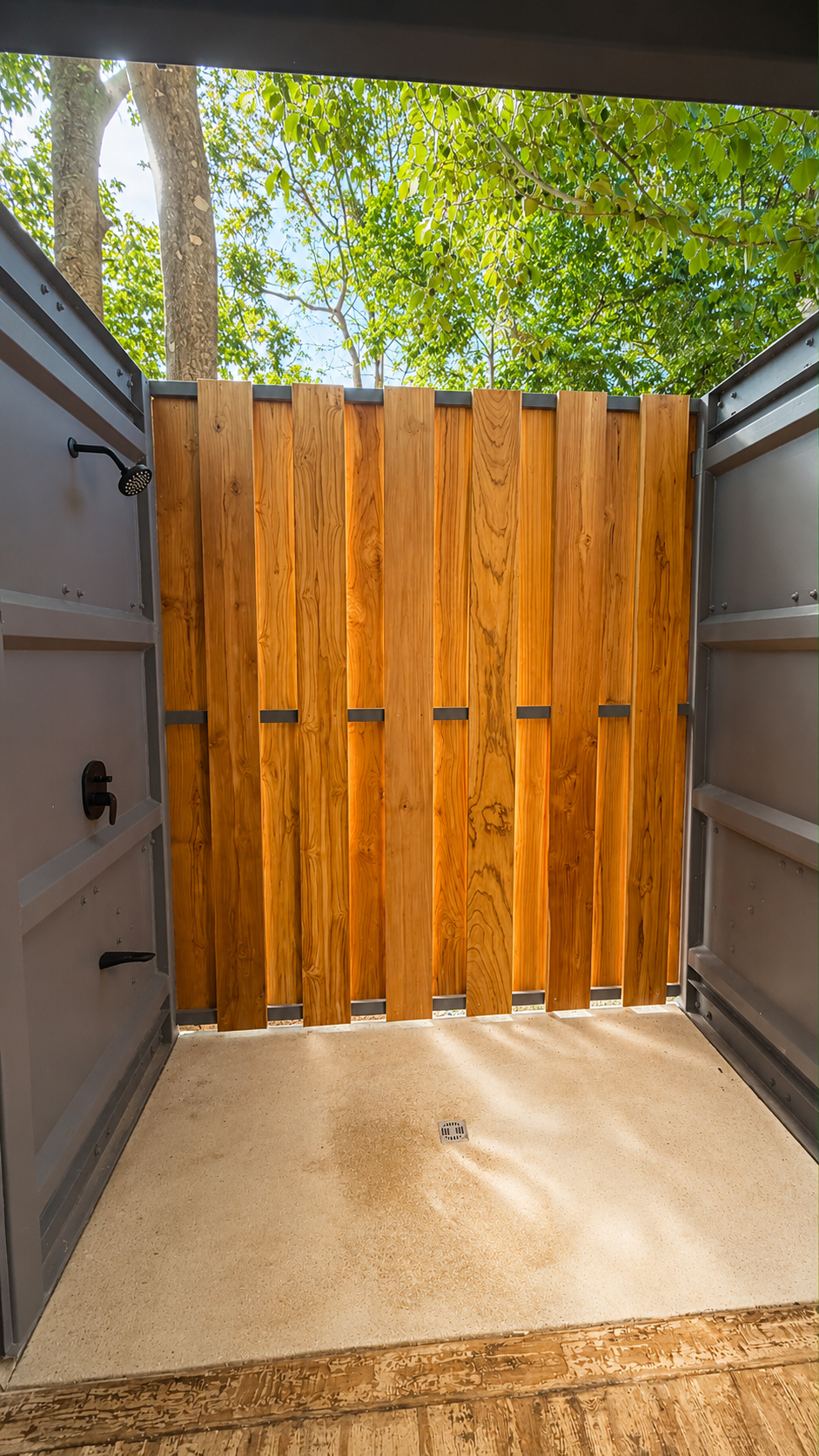 Private outdoor shower enclosed by teak slats with tropical trees visible above