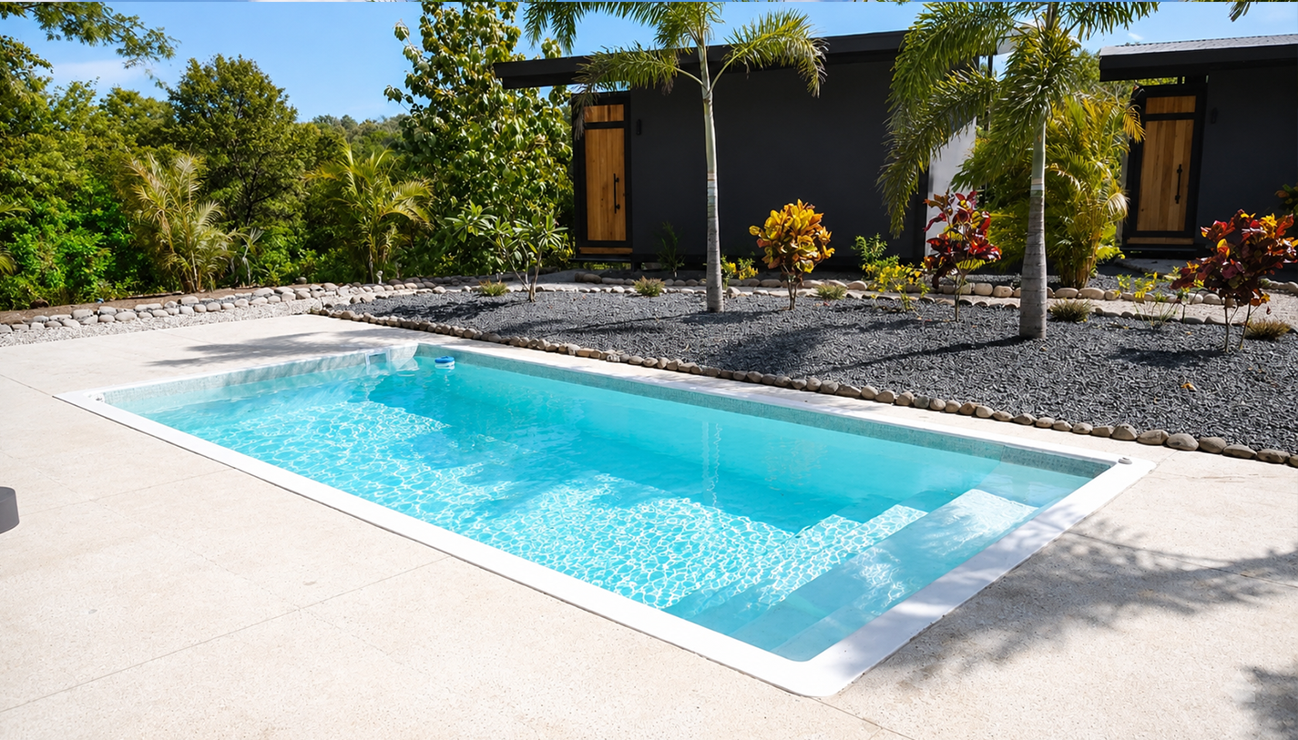 Wide view of the pool deck with the bungalows, landscaped gardens and palm trees under a bright sky