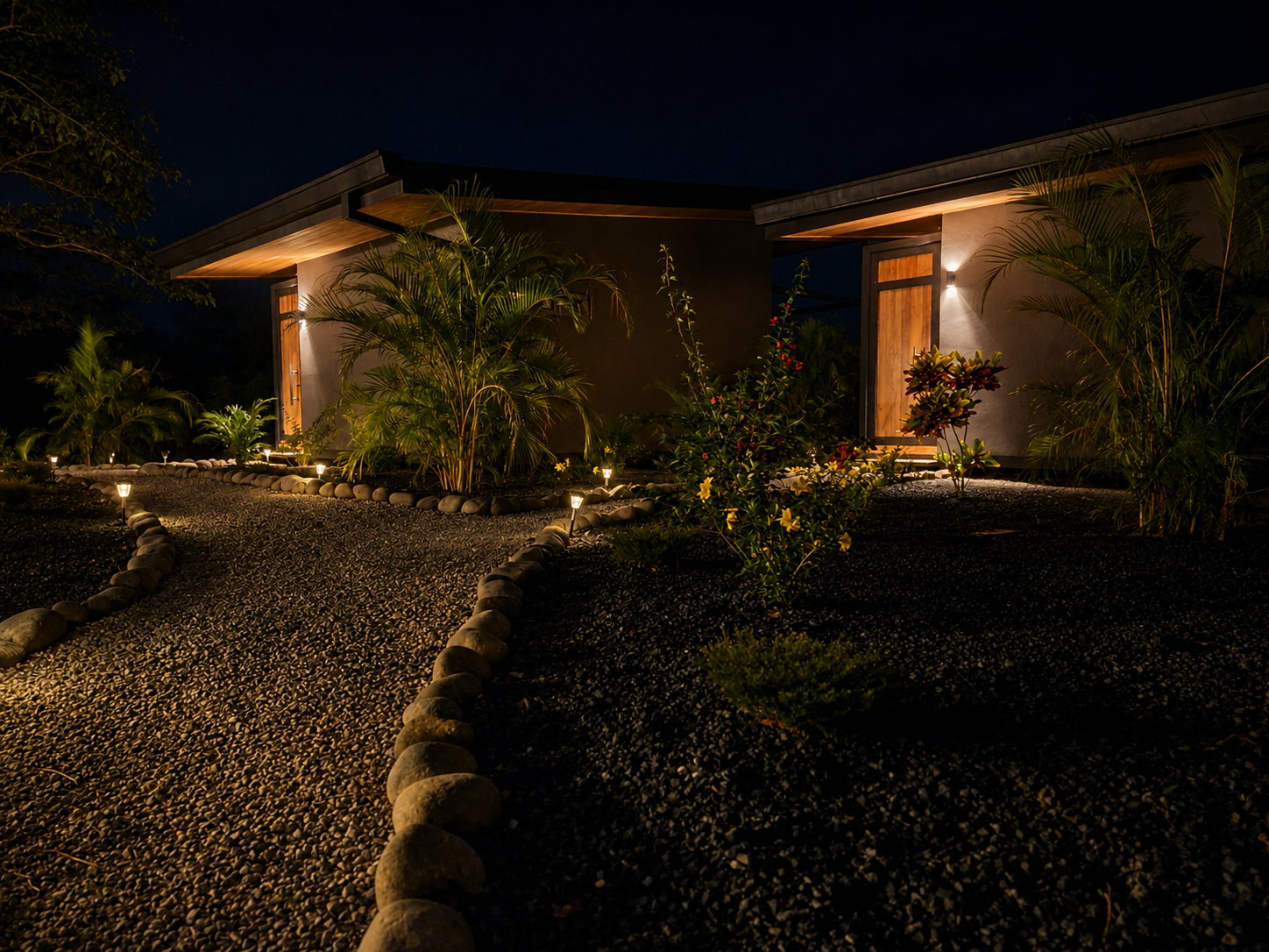 Lit stone pathway between the two bungalows after dark