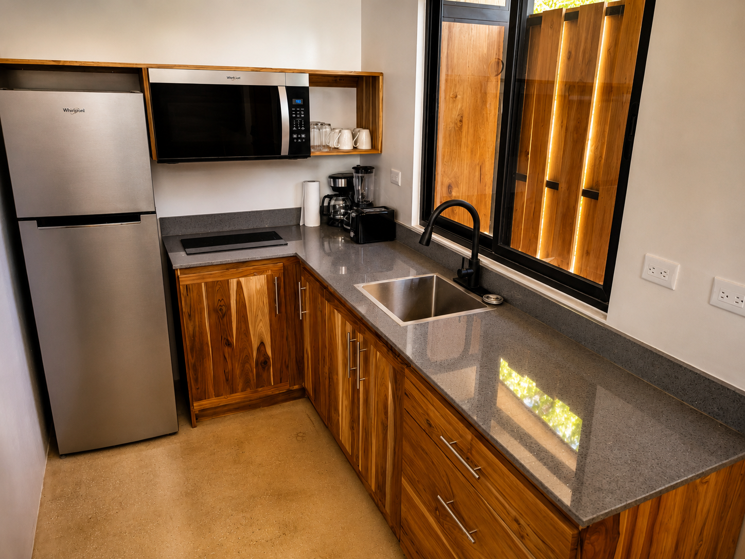 Kitchenette with teak cabinetry, stone counters, refrigerator, microwave and coffee maker