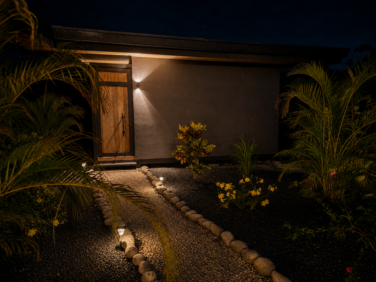 Bungalow entry lit at night with garden lighting