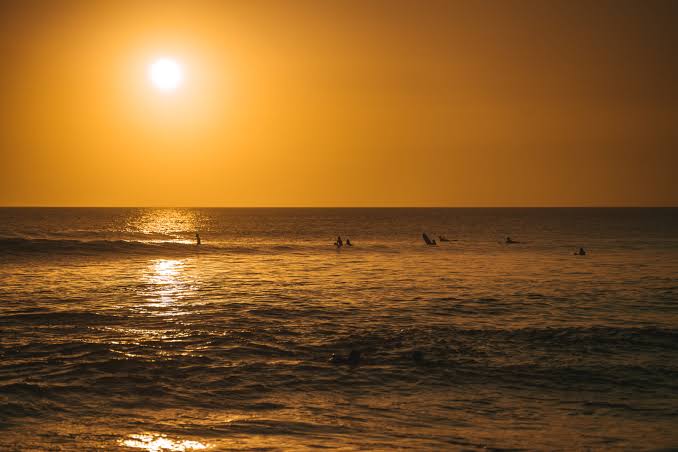 Surfers waiting on the lineup in golden evening light