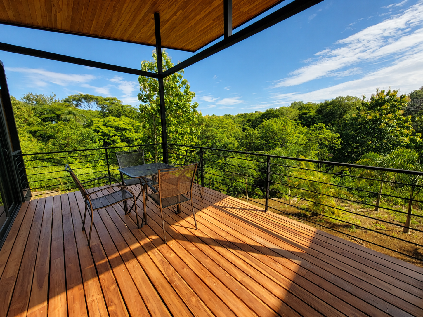 Private teak deck with table and chairs overlooking the tropical canopy